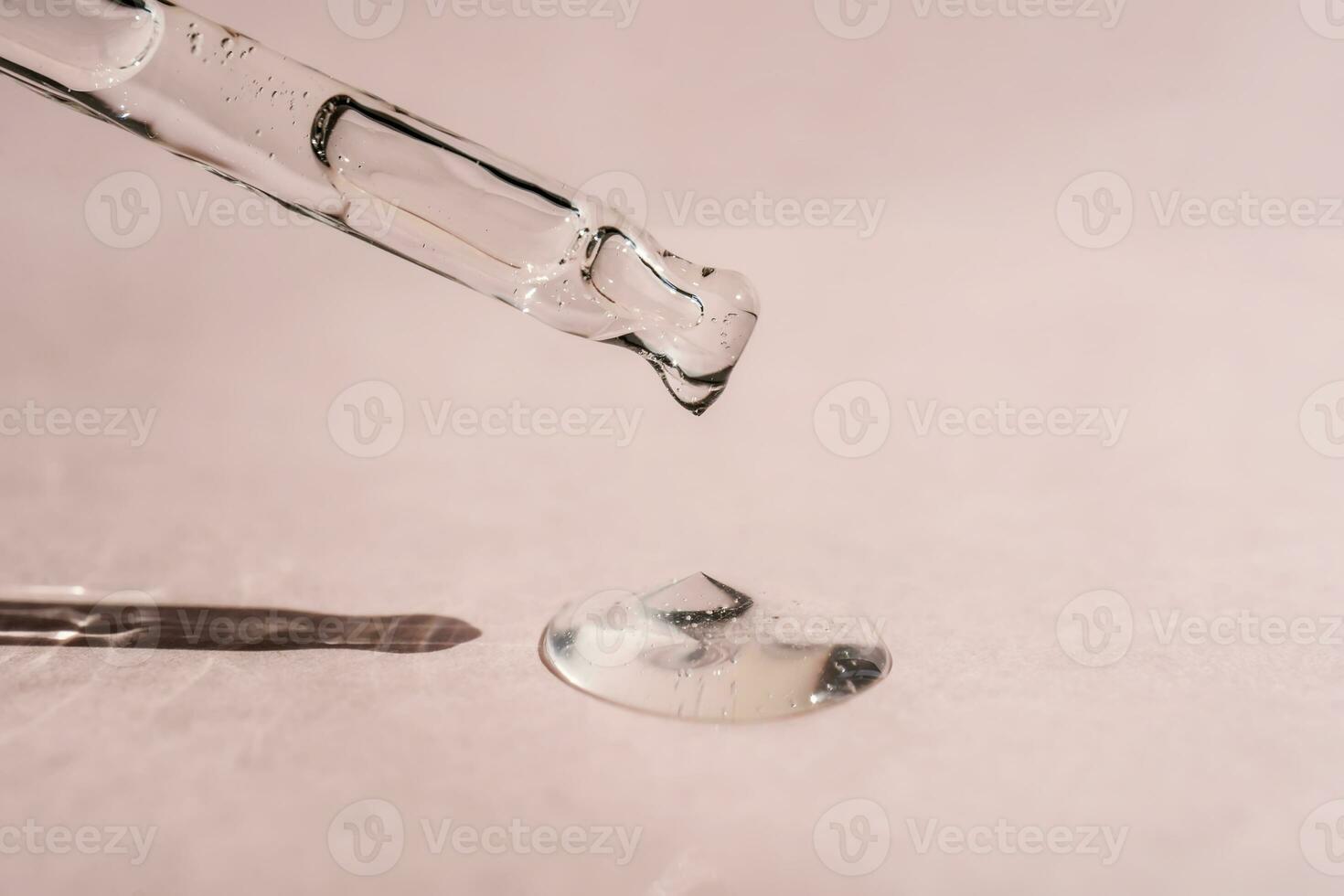 A drop of cosmetic oil falls from the pipette photo