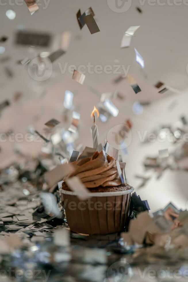 A cupcake with a candle stands on a white background with a shadow. photo