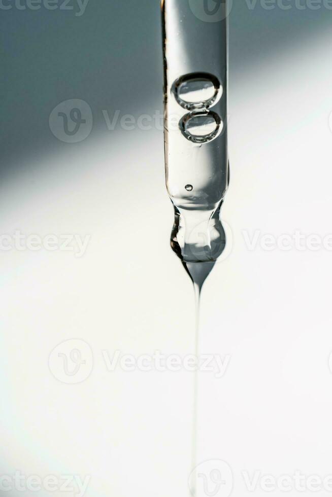 A drop of cosmetic oil falls from the pipette photo