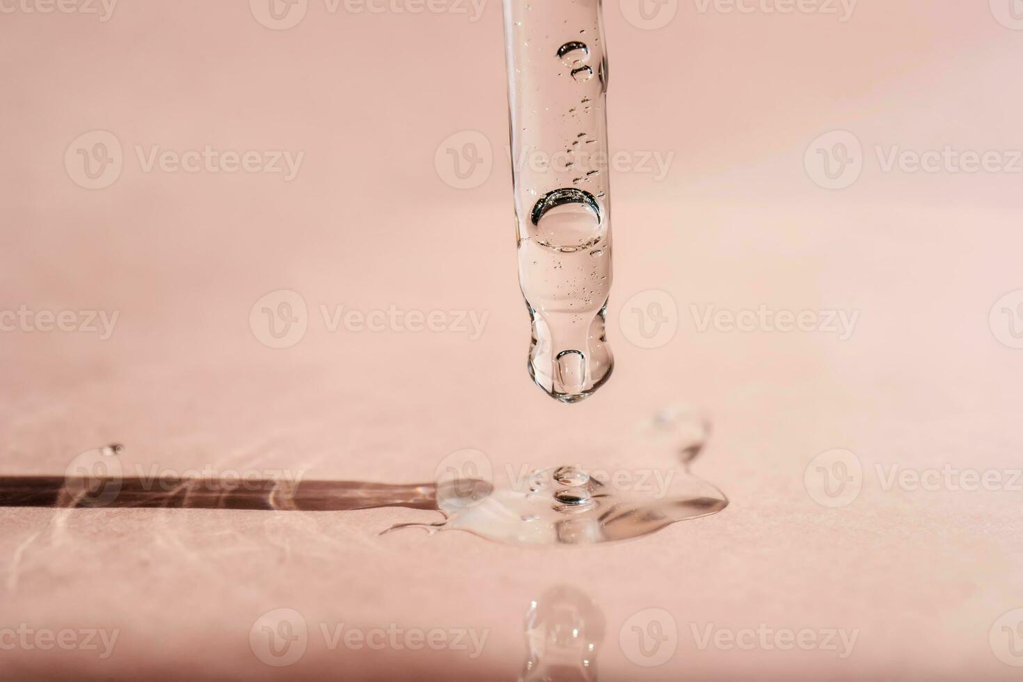 A drop of cosmetic oil falls from the pipette photo