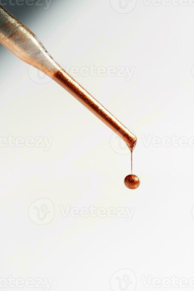 A drop of foundation drips from the pipette. photo