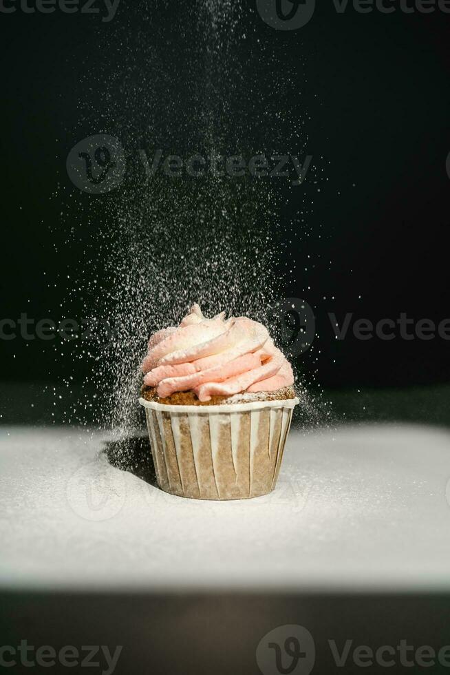 Cupcake on a dark background, which is sprinkled on top. photo