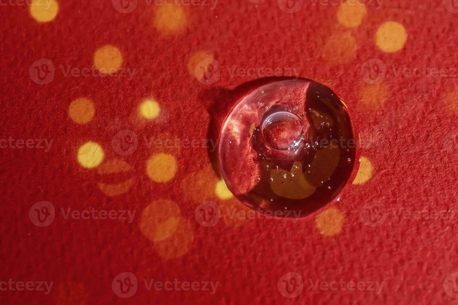 A drop of serum on a red background with bokeh. photo