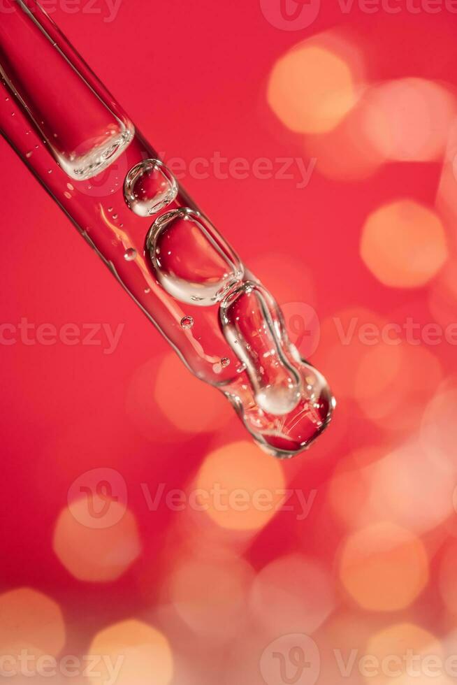Pipette with serum on a red holiday background with bokeh. photo