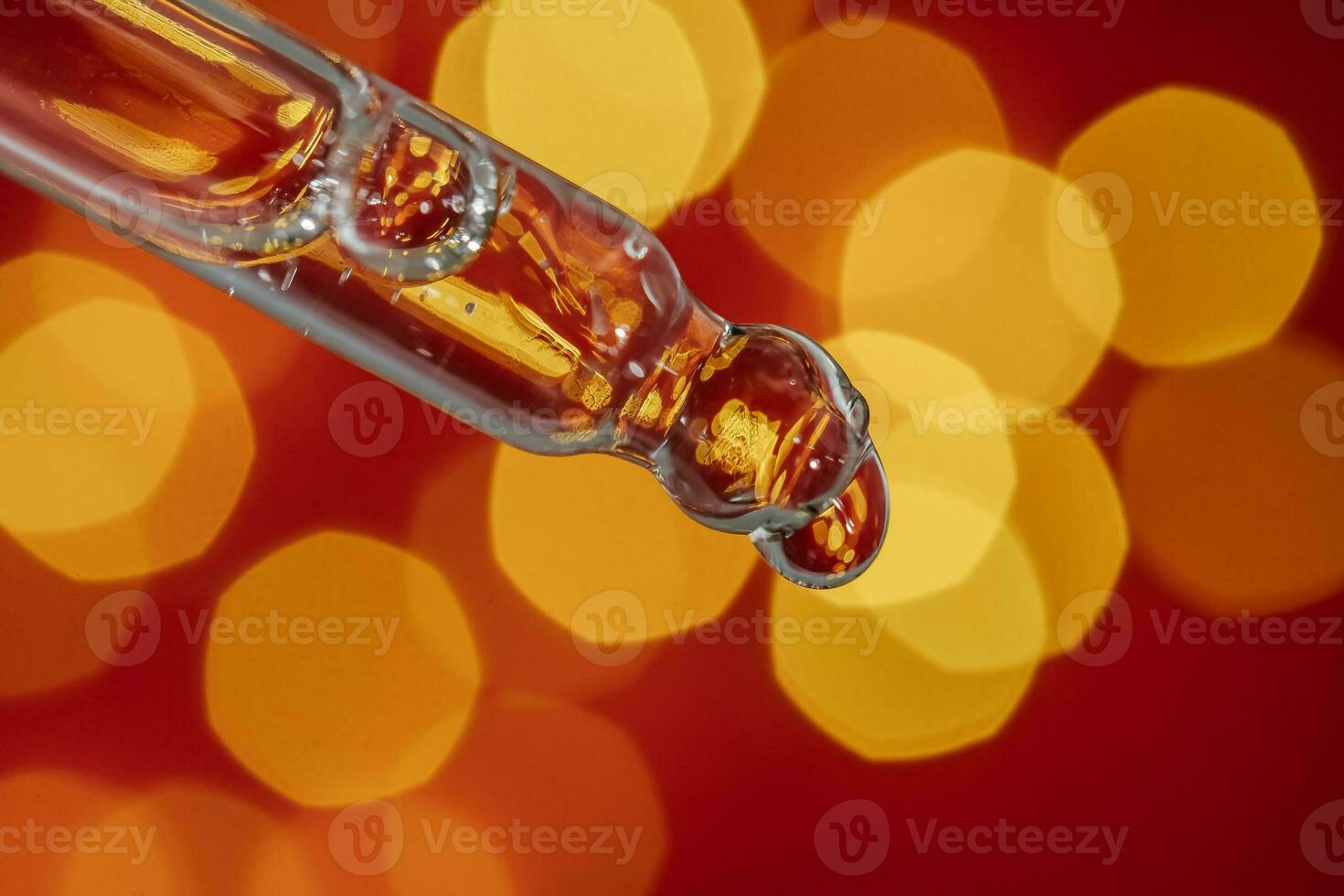 Pipette with serum on a red holiday background with bokeh. photo