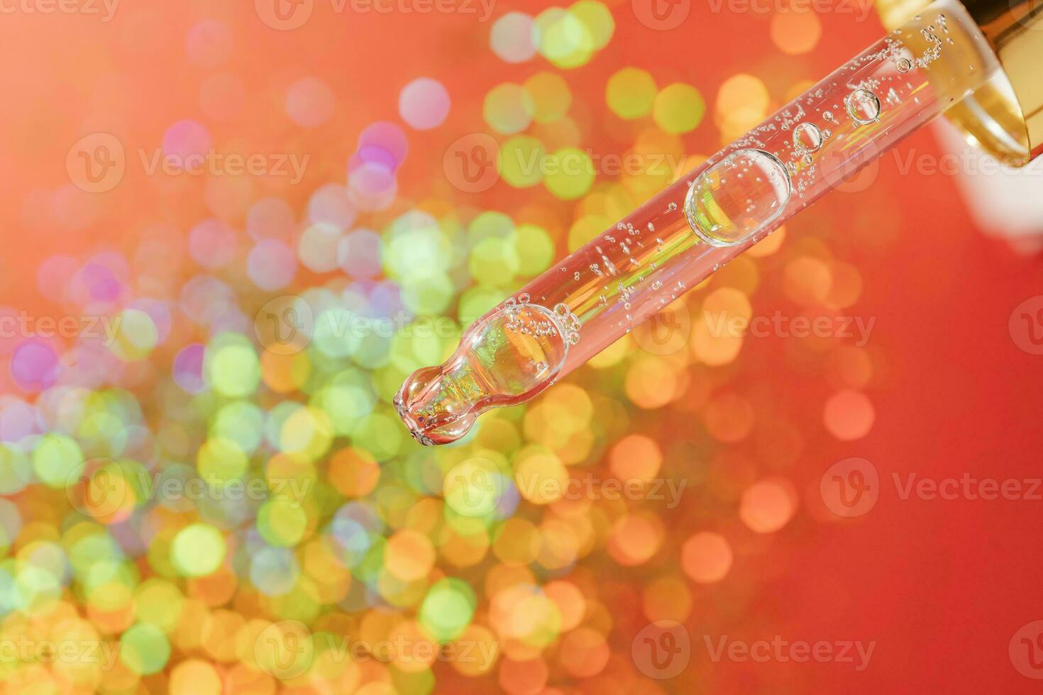 Pipette with serum on a red holiday background with bokeh. photo