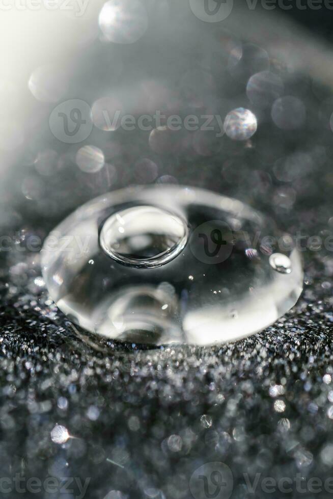 A drop of cosmetic gel on a black shining background. photo