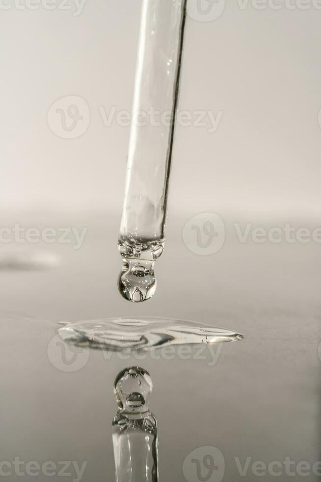 The texture of serum or oil with a pipette on a grey background. photo