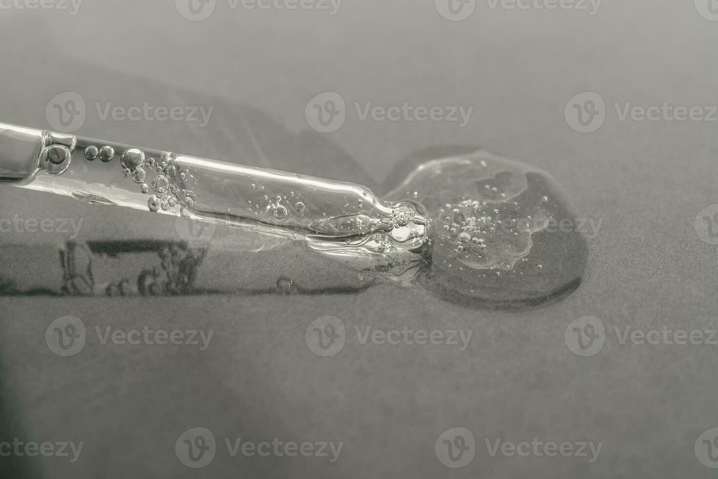 The texture of serum or oil with a pipette on a grey background. photo