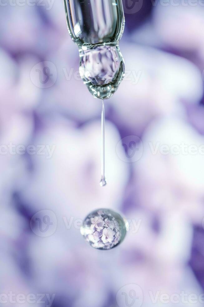 A drop of cosmetic oil falls from the pipette on a purple floral background. photo