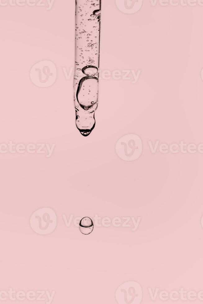 Transparent pipette with cosmetics on a pink background. photo
