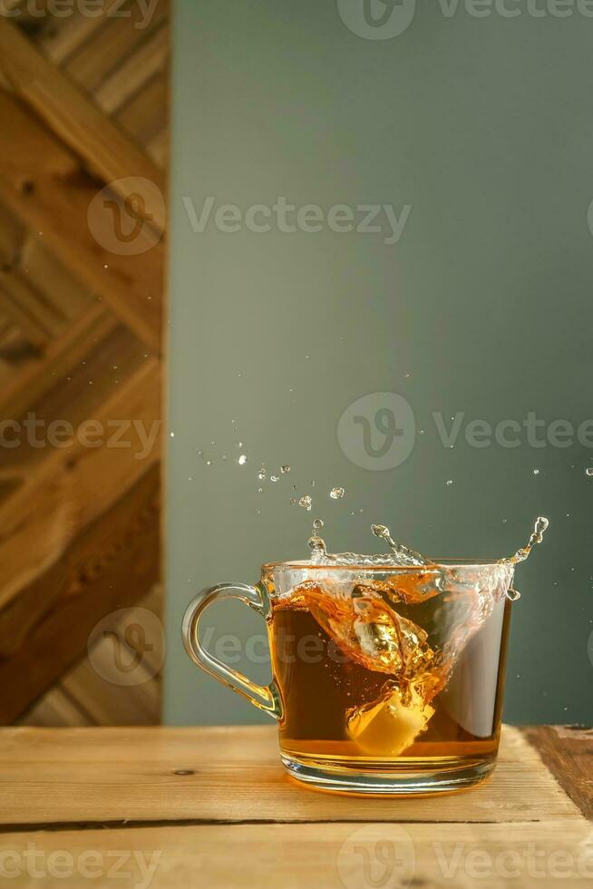 Transparent mug with tea and splashes on a green background. photo