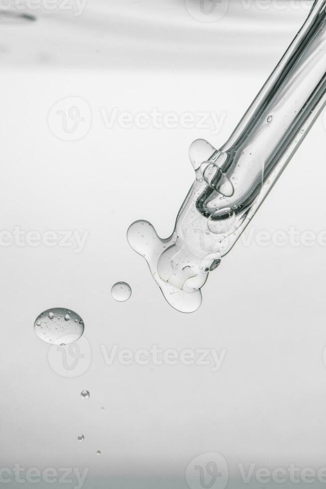 Pipette with cosmetic product in water with bubbles. photo