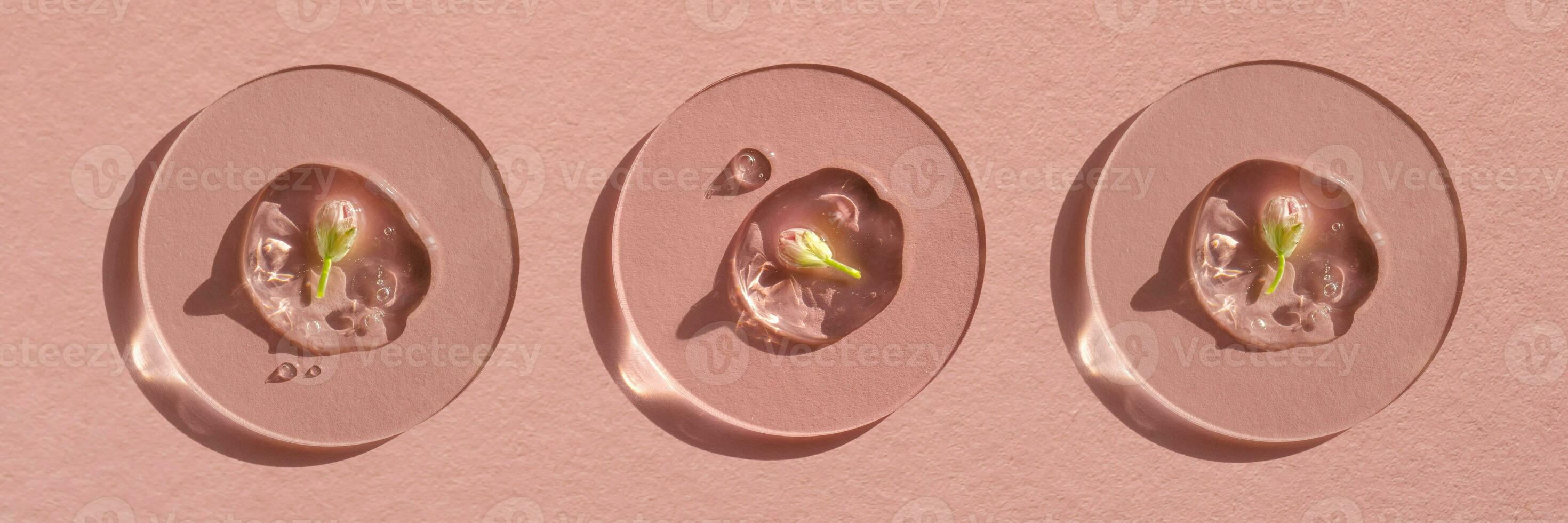 A drop of cosmetic gel with a flower on a pink background. photo