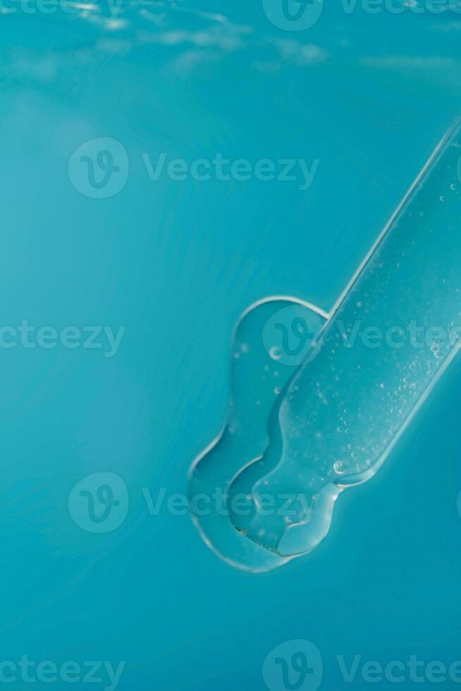 Pipette with cosmetic product in water with bubbles. photo