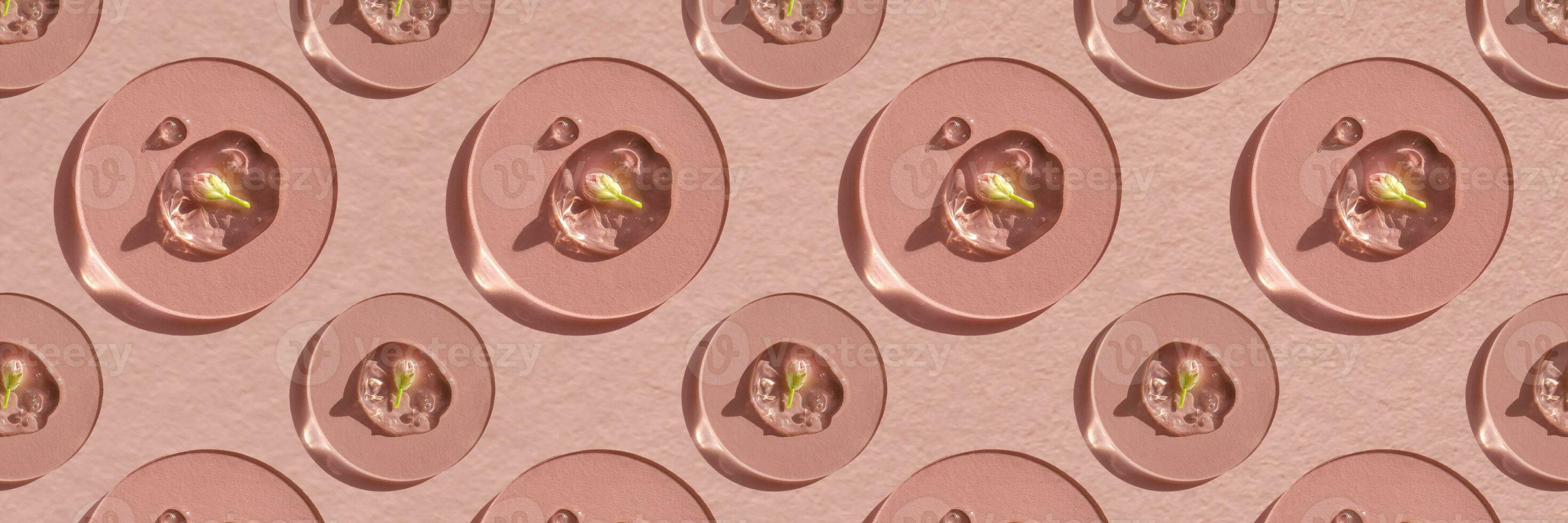 A drop of cosmetic gel with a flower on a pink background. photo