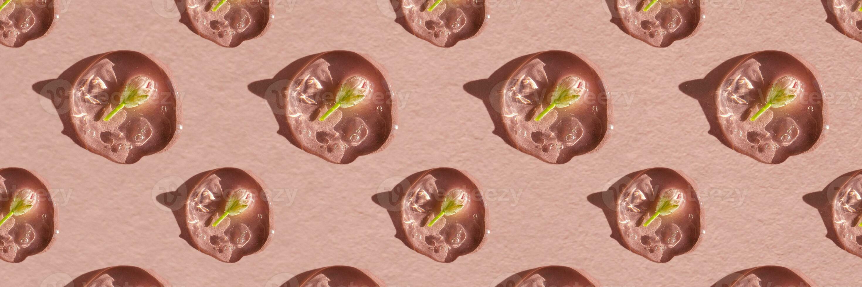 A drop of cosmetic gel with a flower on a pink background. photo
