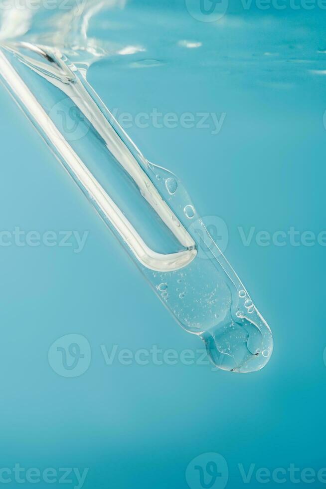 Pipette with cosmetic product in water with bubbles. photo