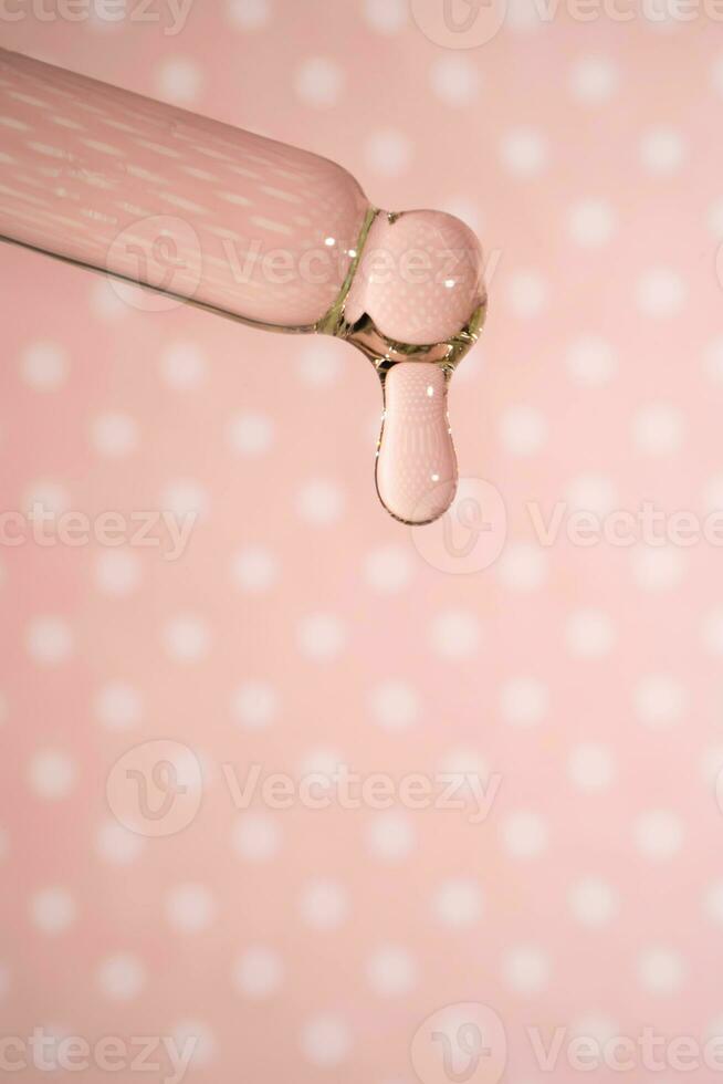 A dripping pipette with a drop of cosmetics gel. photo