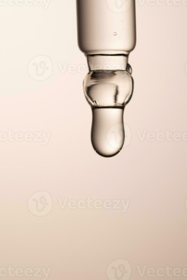 Pipette with serum, gel, oil or other cosmetic product on a beige background. photo