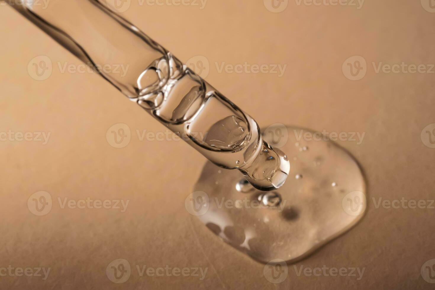 Pipette with serum, gel, oil or other cosmetic product on a beige background. photo