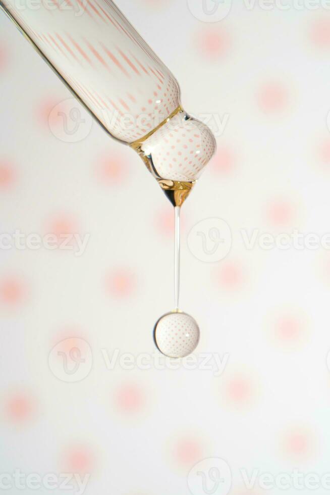 A dripping pipette with a drop of cosmetics gel. photo