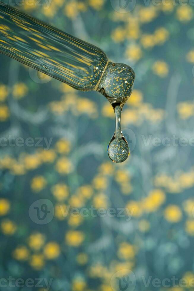 A dripping pipette with a drop of cosmetics gel. photo