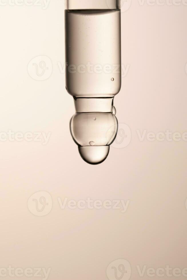 Pipette with serum, gel, oil or other cosmetic product on a beige background. photo