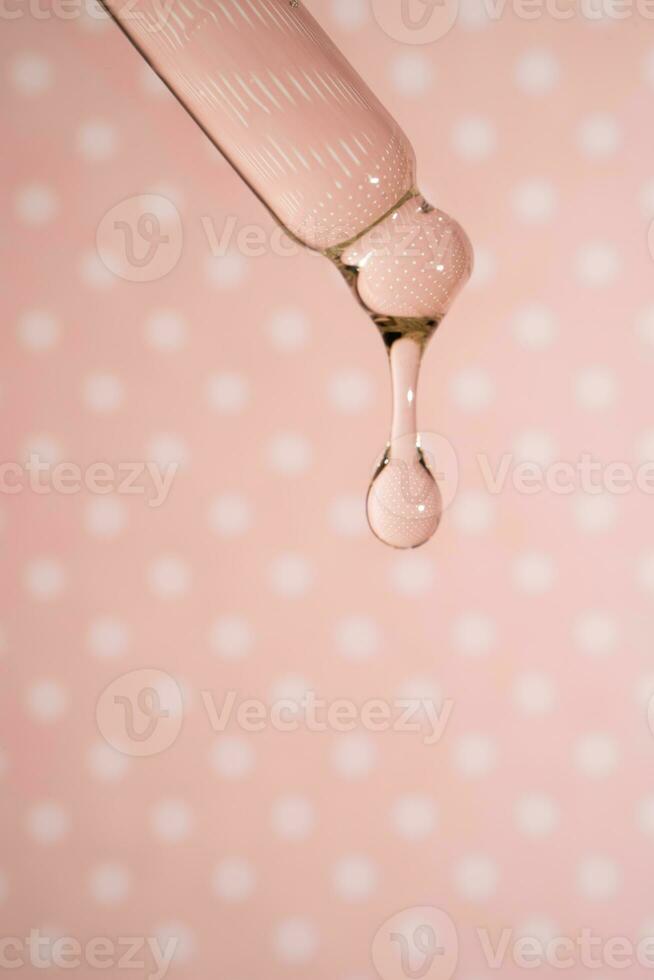 A dripping pipette with a drop of cosmetics gel. photo