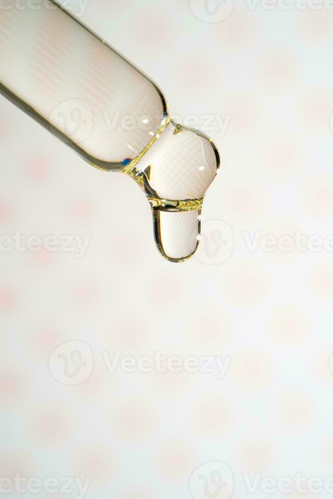 A dripping pipette with a drop of cosmetics gel. photo