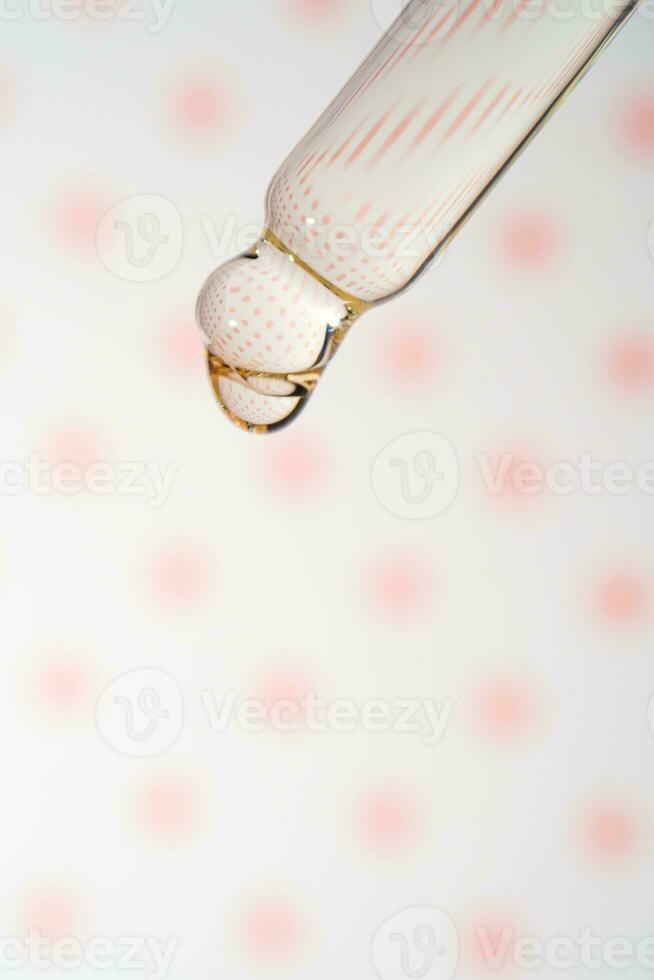 A dripping pipette with a drop of cosmetics gel. photo