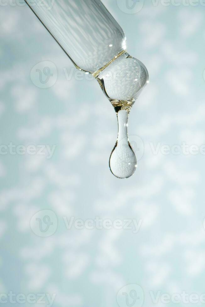 A dripping pipette with a drop of cosmetics gel. photo