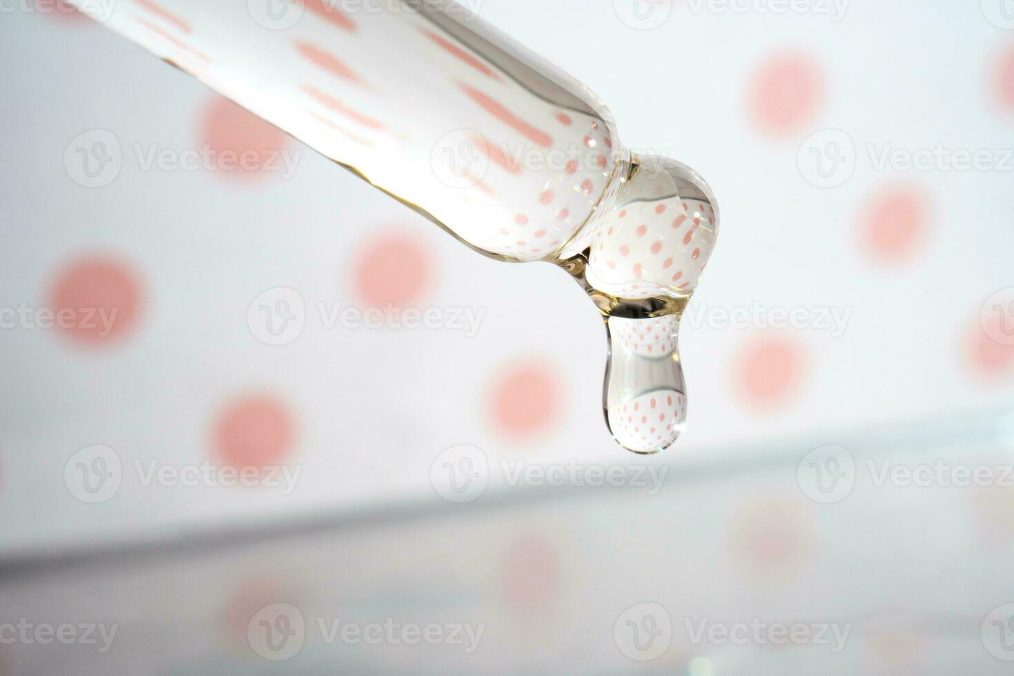 A dripping pipette with a drop of cosmetics gel. photo