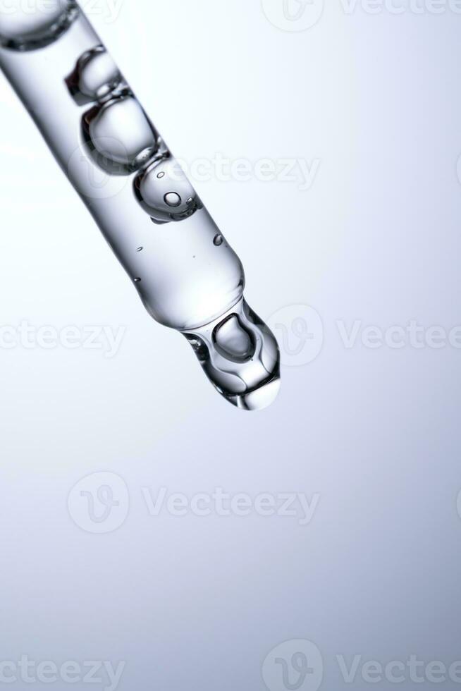 Pipette with serum or other cosmetic product on a blue background. photo