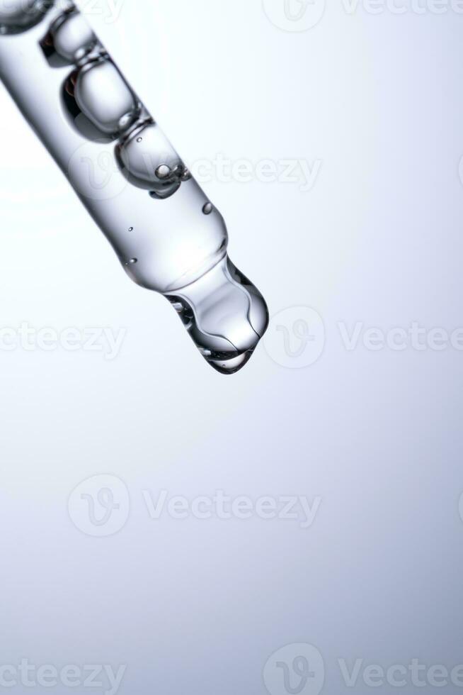 Pipette with serum or other cosmetic product on a blue background. photo