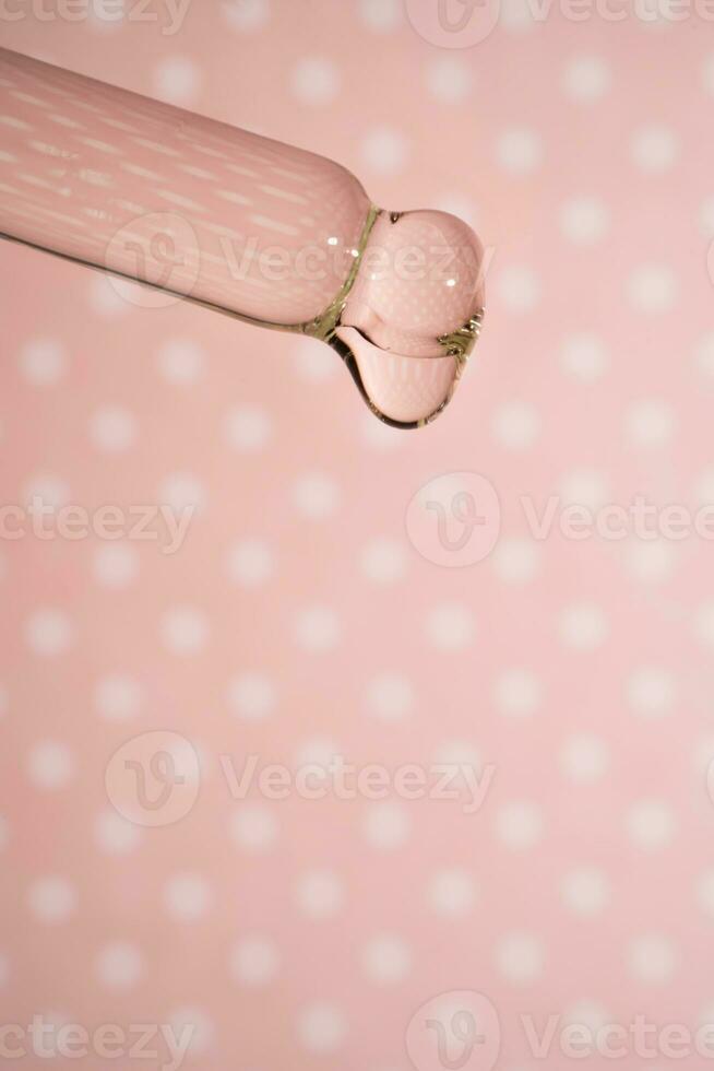 A dripping pipette with a drop of cosmetics gel. photo