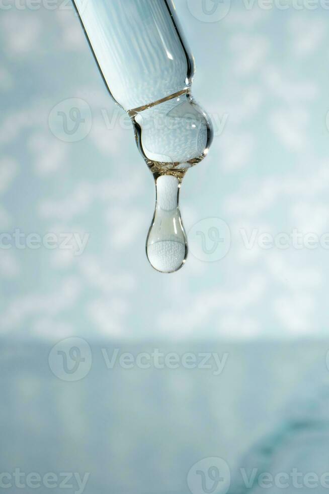 A dripping pipette with a drop of cosmetics gel. photo