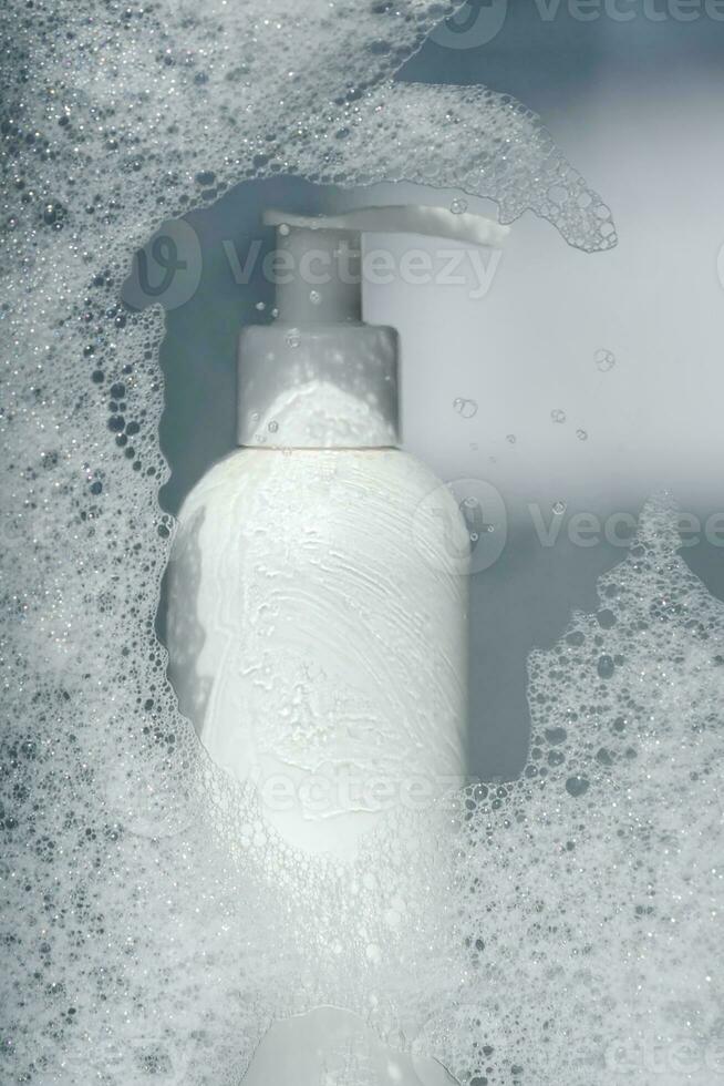 A bottle of gel or shampoo on a background of white foam. photo