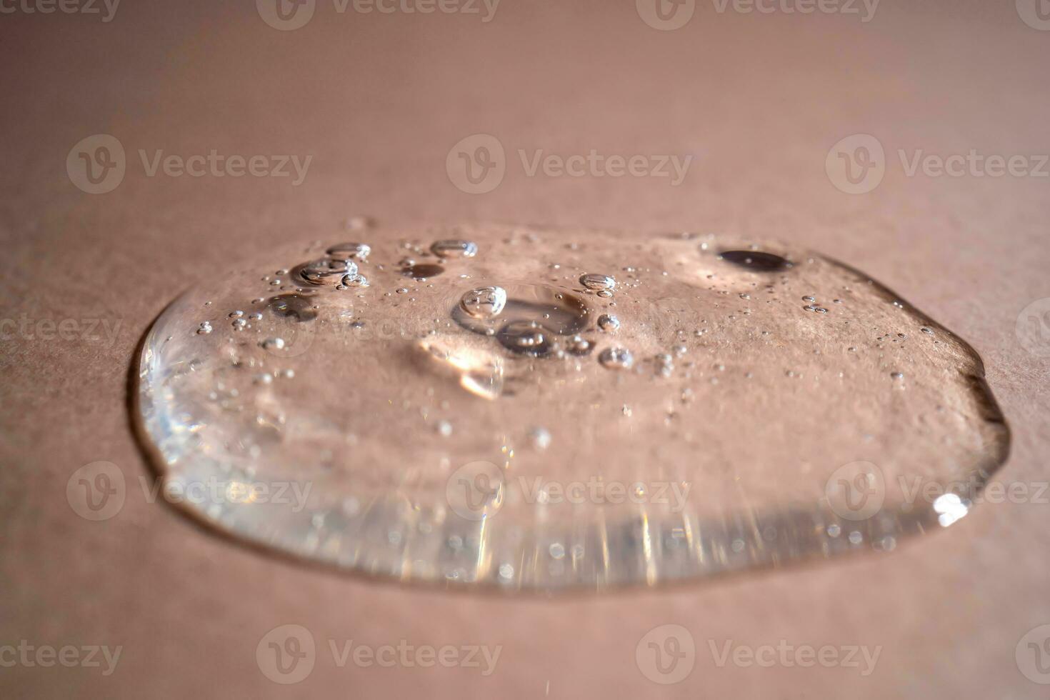 A drop of serum with bubbles on a beige background. photo