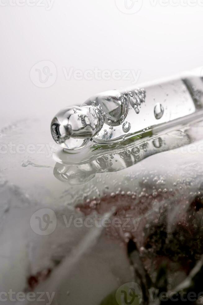 Pipette on a large piece of ice with frozen flowers. photo