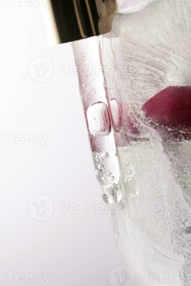 Pipette on a large piece of ice with frozen flowers. photo