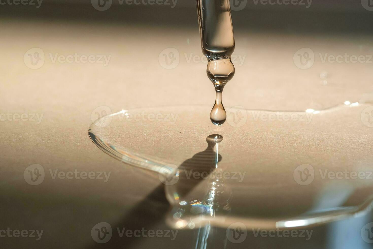 A Dripping Pipette of cosmetic gel on a beige background. photo