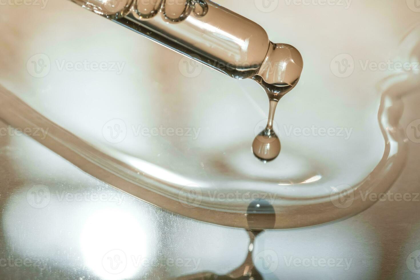 A Dripping Pipette of cosmetic gel on a beige background. photo