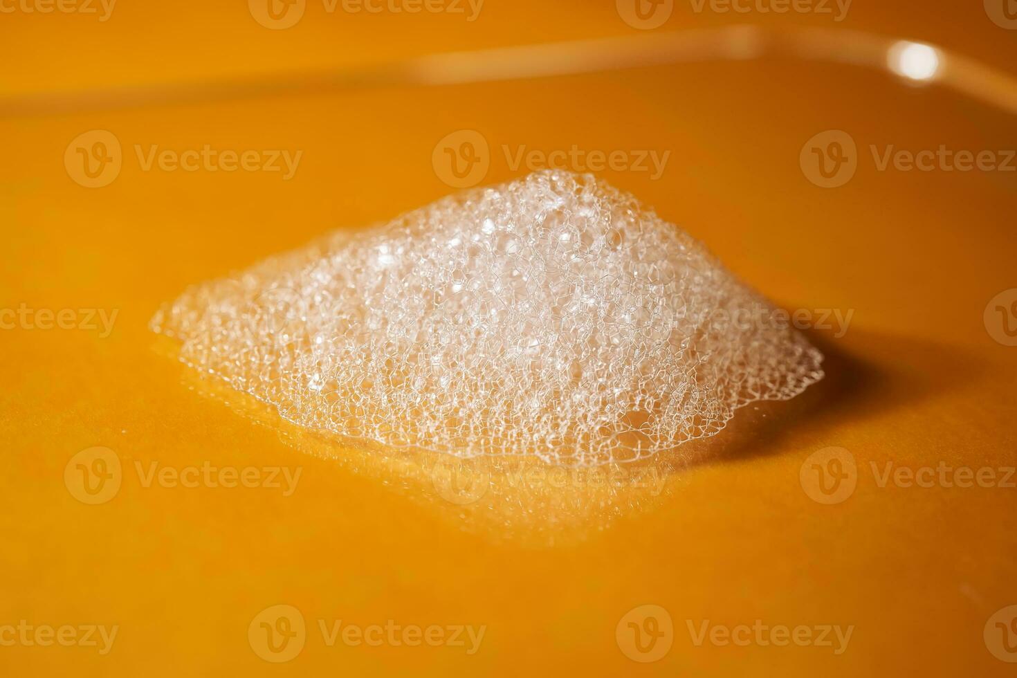 White foam from shampoo or shower gel on a bright yellow background. photo