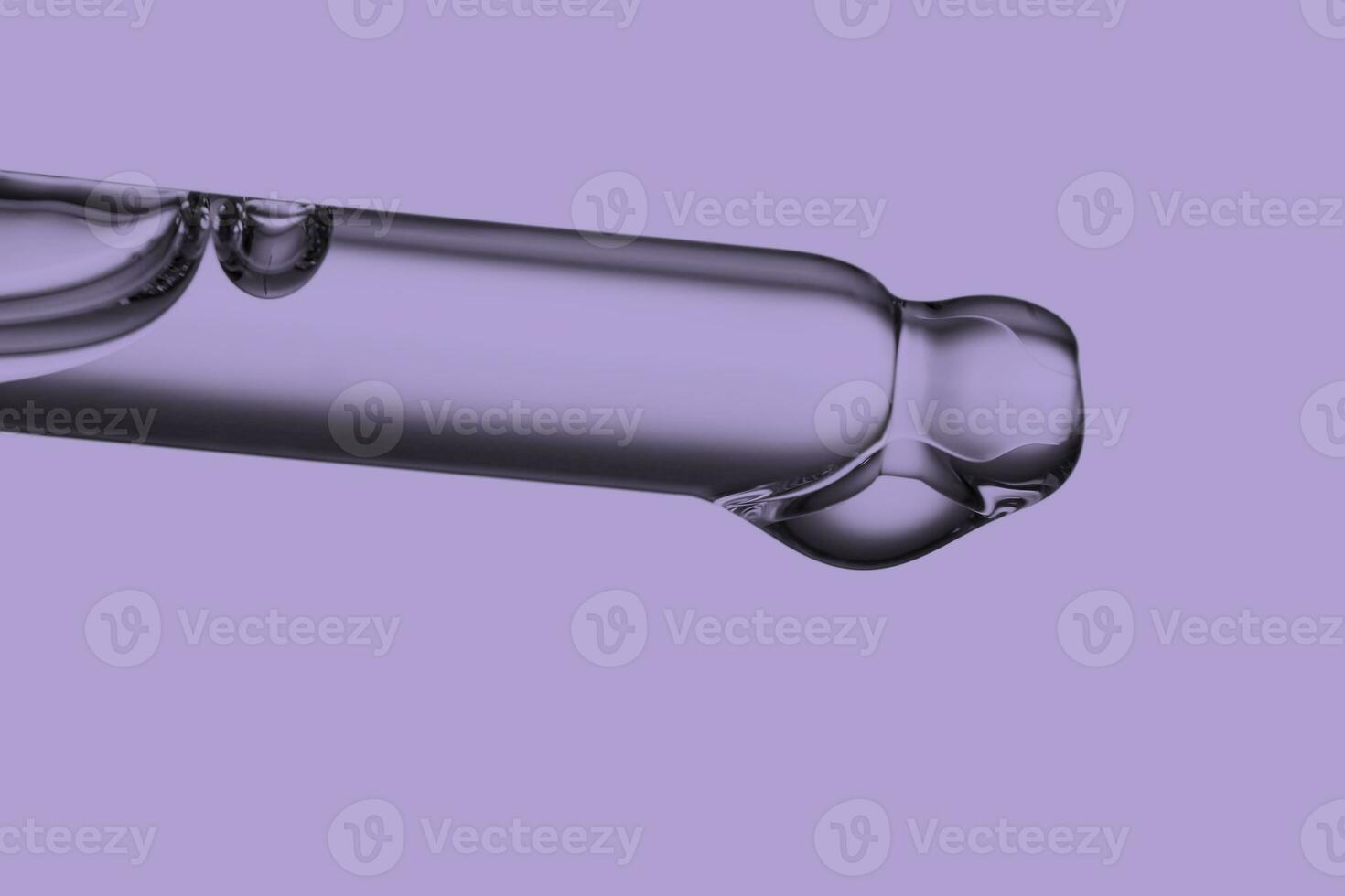 Pipette with a drop of cosmetic product on a purple background. photo