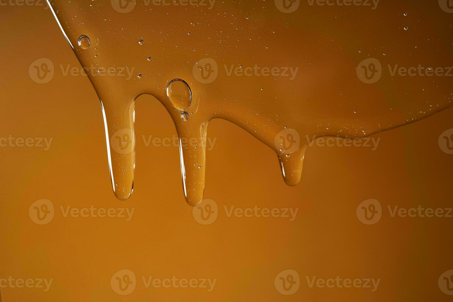 A drop of body gel or shampoo flowing down on a yellow saturated background. Texture. photo