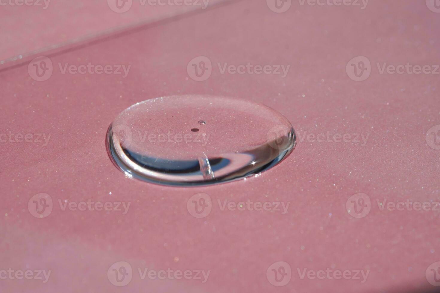 A drop of cosmetics or perfume on a pink background. photo