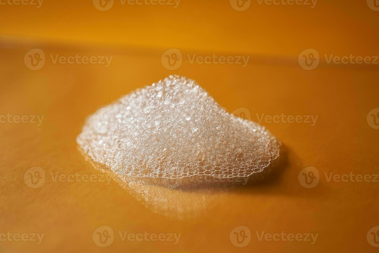 White foam from shampoo or shower gel on a bright yellow background. photo