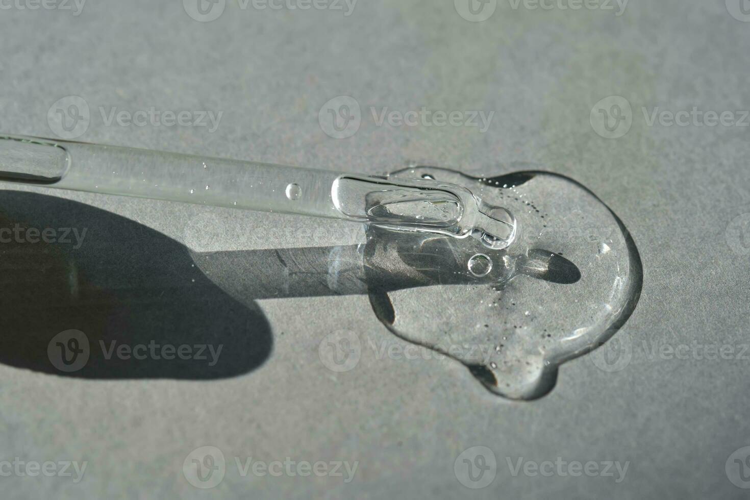 Pipette with spilled cosmetic oil or serum on a gray background. photo