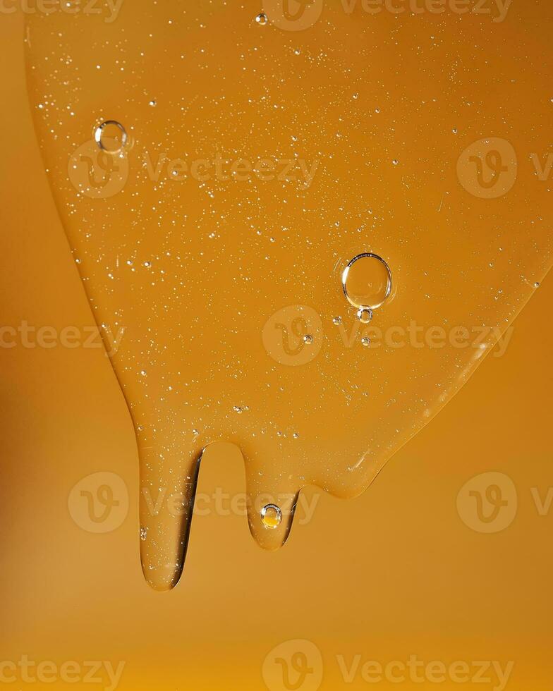 A drop of body gel or shampoo flowing down on a yellow saturated background. Texture. photo